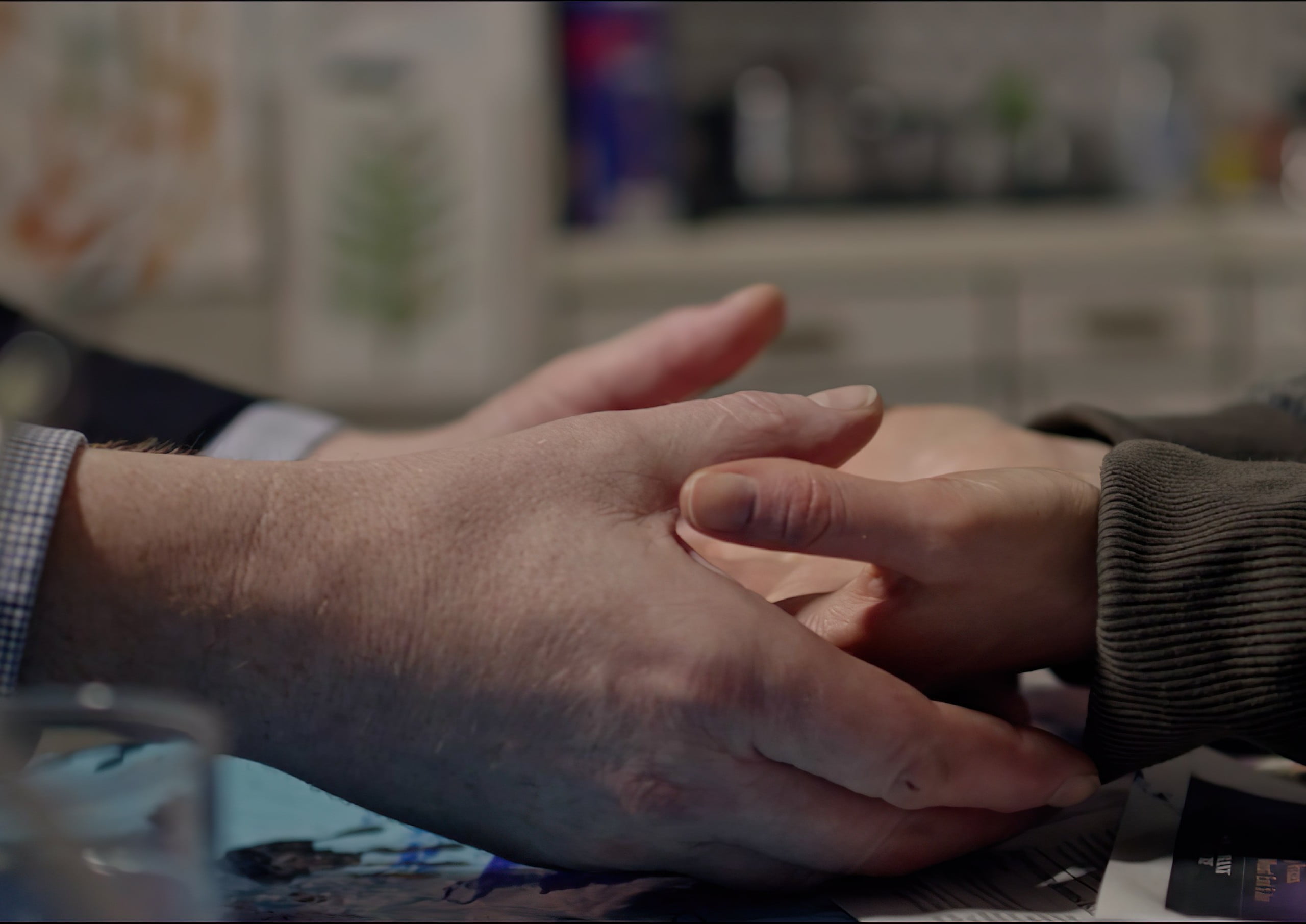 Two pairs of hands holding over a table, from short film Sad Pretty Pictures